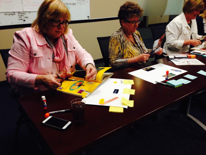 Participants working with magazines, scissors and glue at a table.