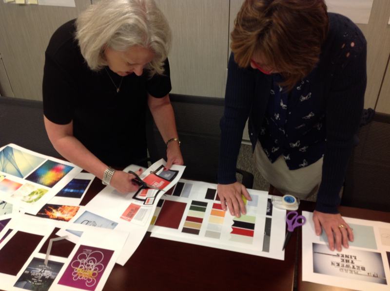 Two people leaning over a table, choosing images and colour swatches.