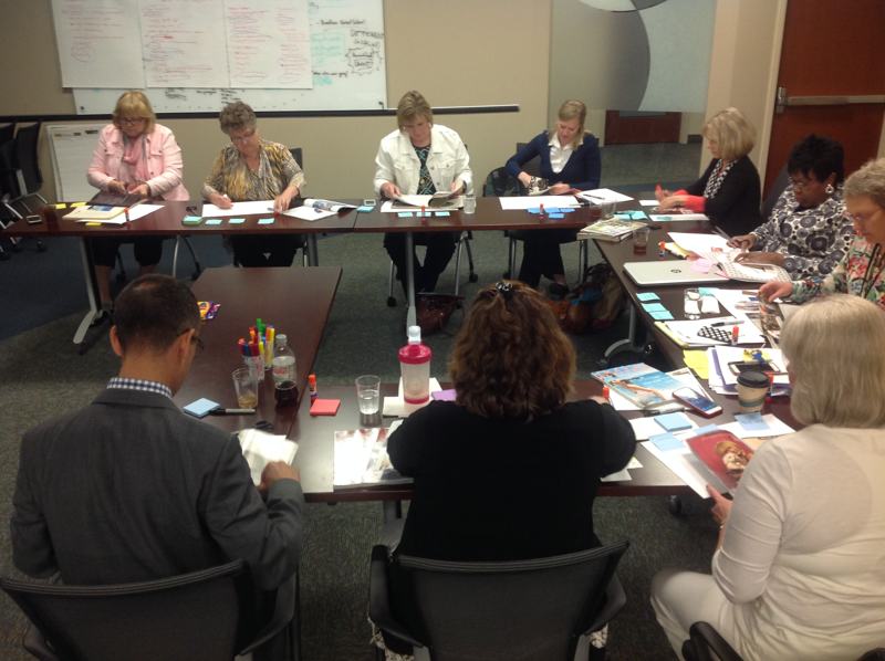 A full room of faculty and staff seated around tables during a working session.