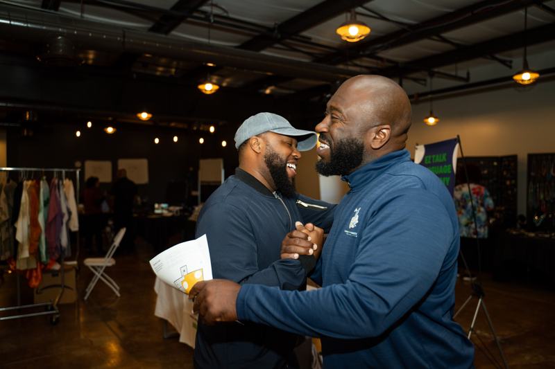Two men laughing together in the event space.