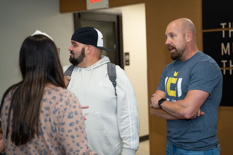 Three people talking in a group, one in an InerG Impact shirt.