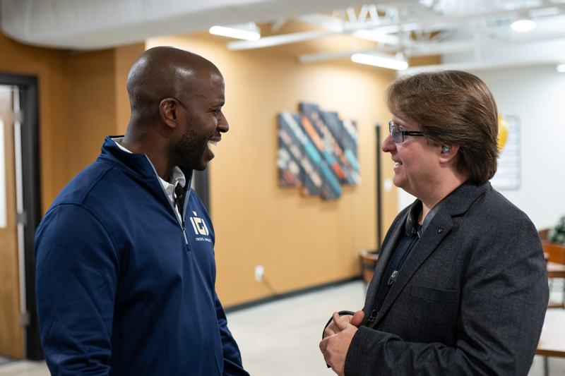 Two people in a friendly conversation in a hallway.