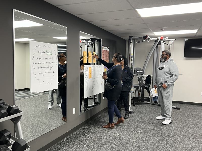 Residents reading and writing on posters taped to a mirrored wall.