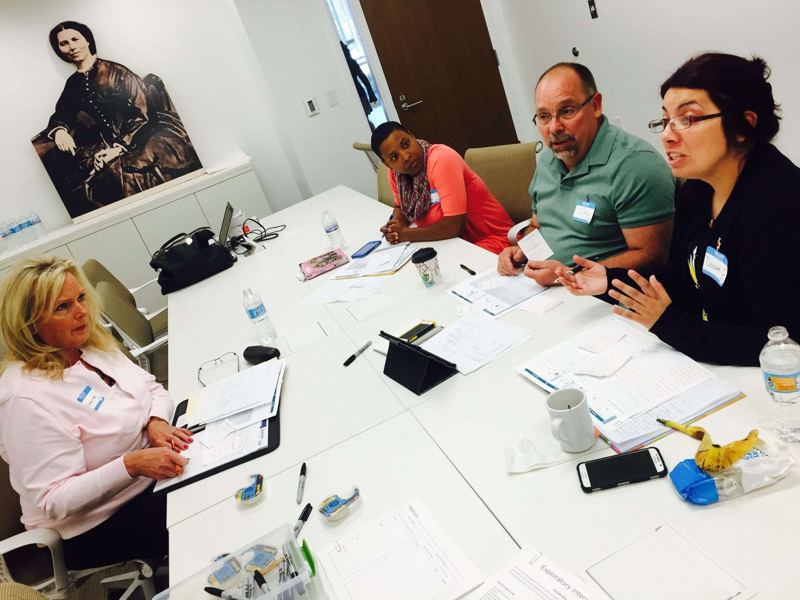 Team members in conversation around a table during a training session.