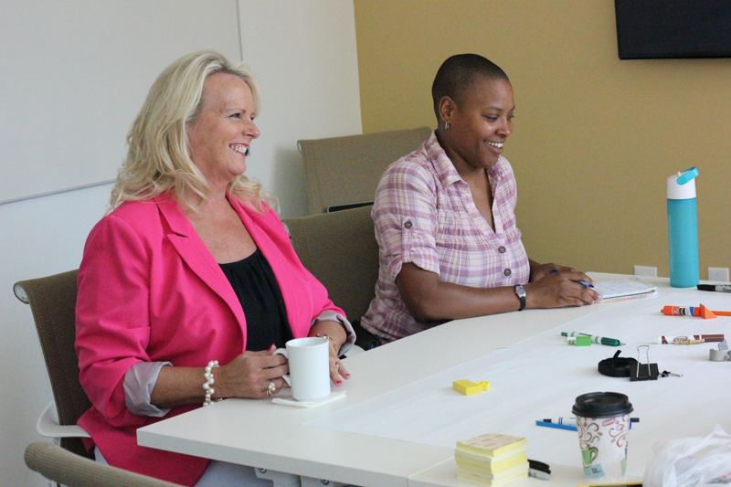 Two participants smiling at a table scattered with prototyping materials.